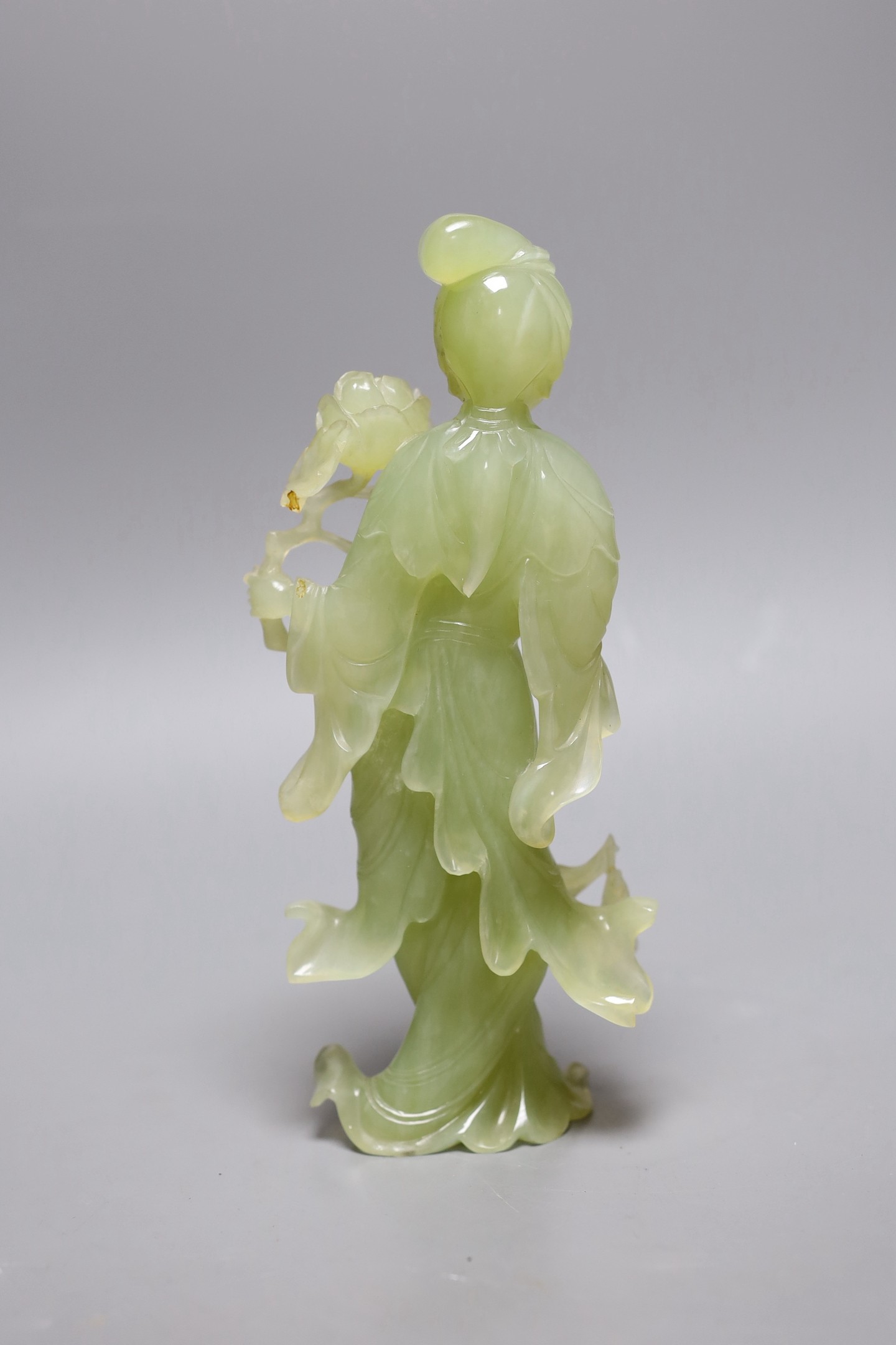 A Chinese carved bowenite figure of a lady holding a floral sprig, 21cm tall